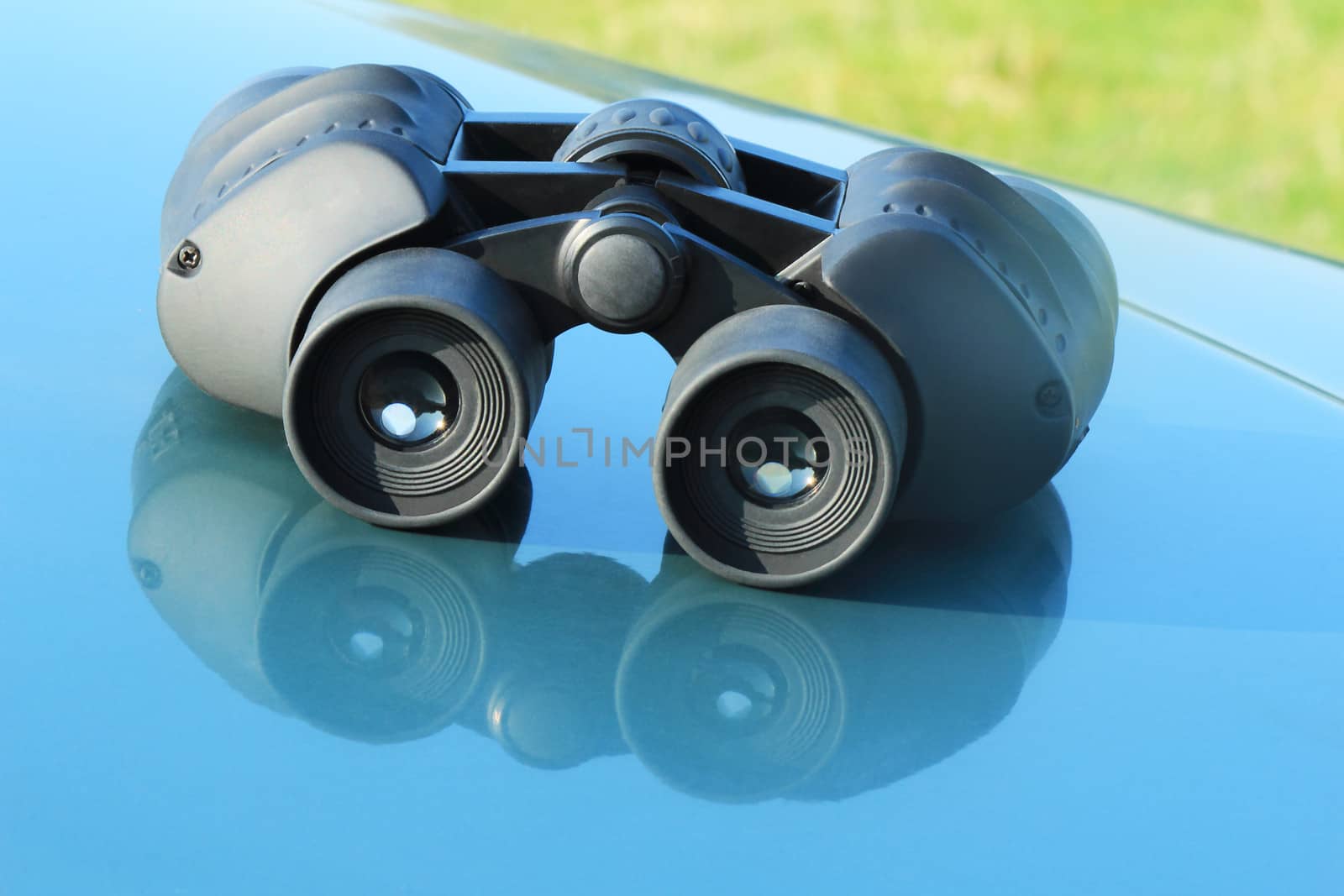 On the hood of a blue car is the binoculars.
