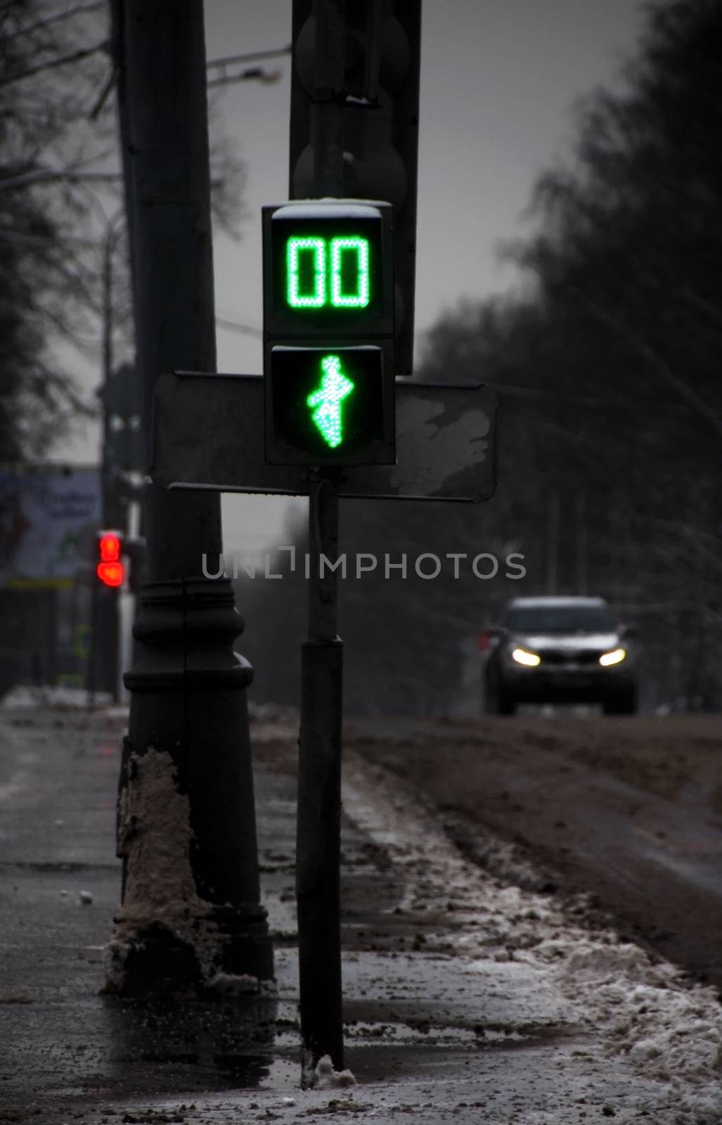 dark gloomy winter morning street in moscow with a traffic light and vehicle