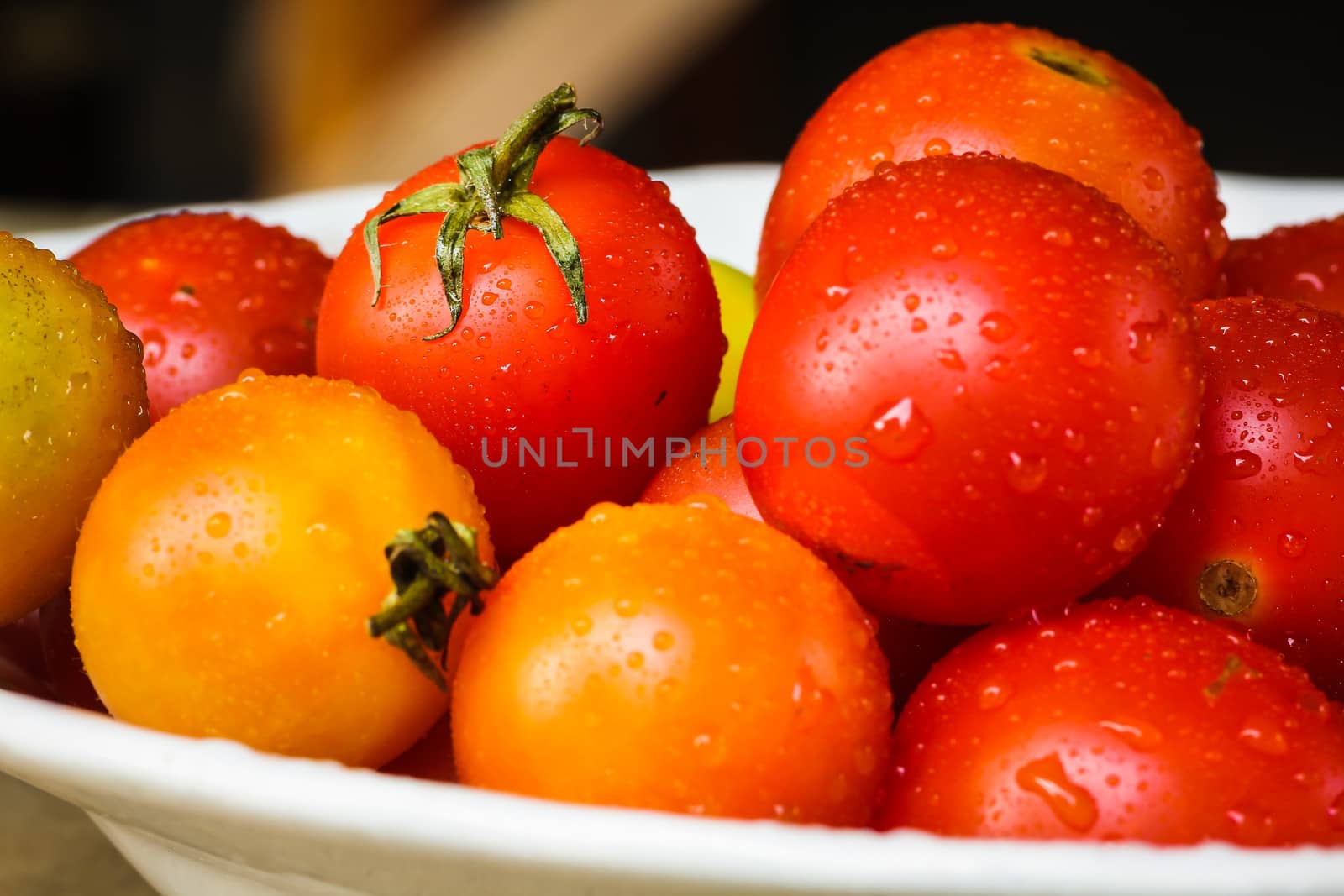 Fresh colorful tomatoes with dew drops close up.