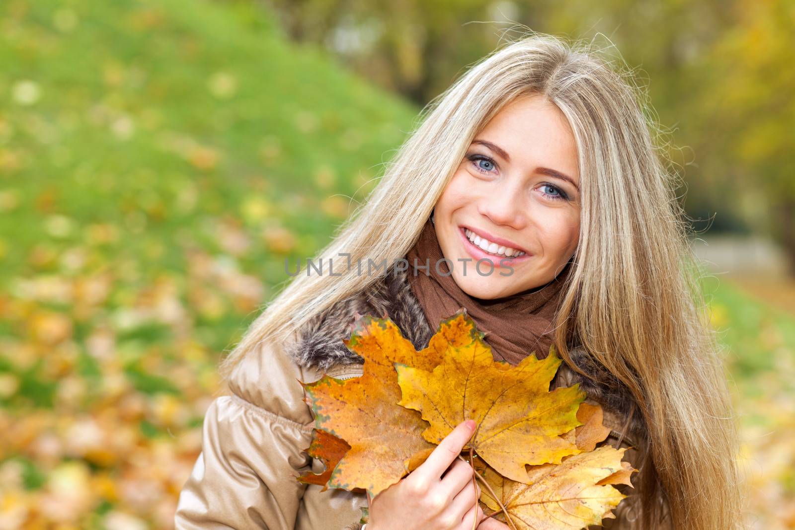 Closeup portrait of a nice woman with leaves of autumn