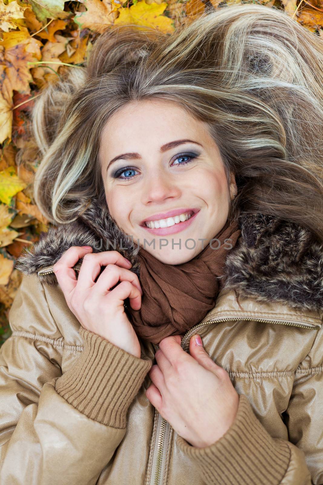 Closeup portrait of a nice young woman surrounded by autumn leaves