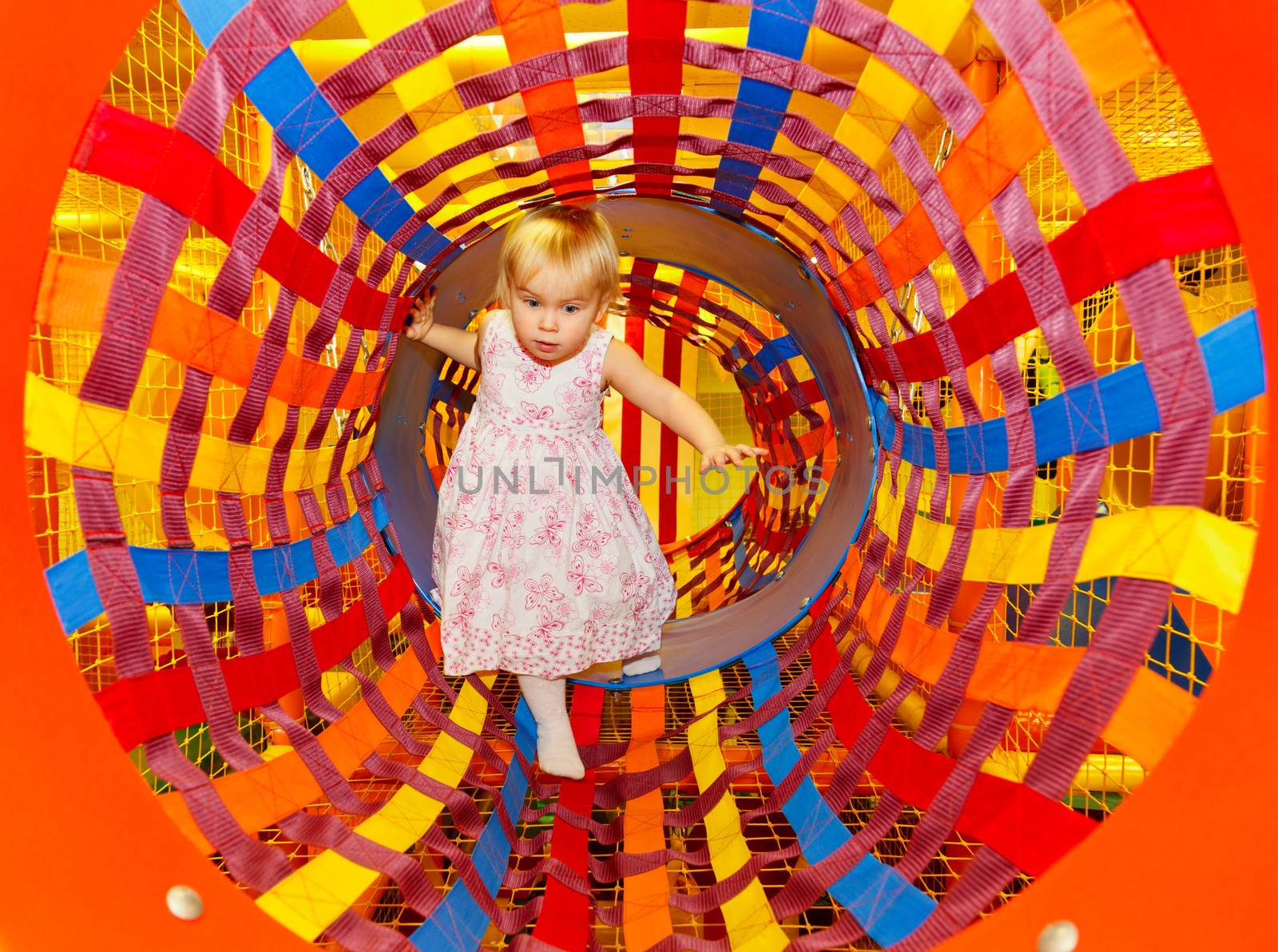 Little girl playing in a tunnel of maze playground