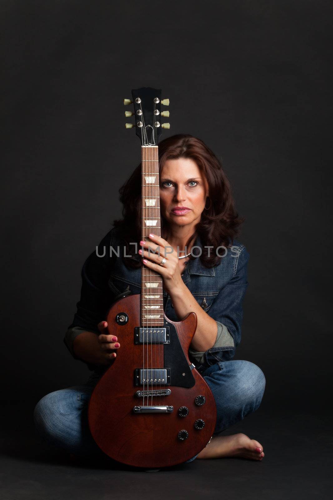 brunette woman on black with a guitar