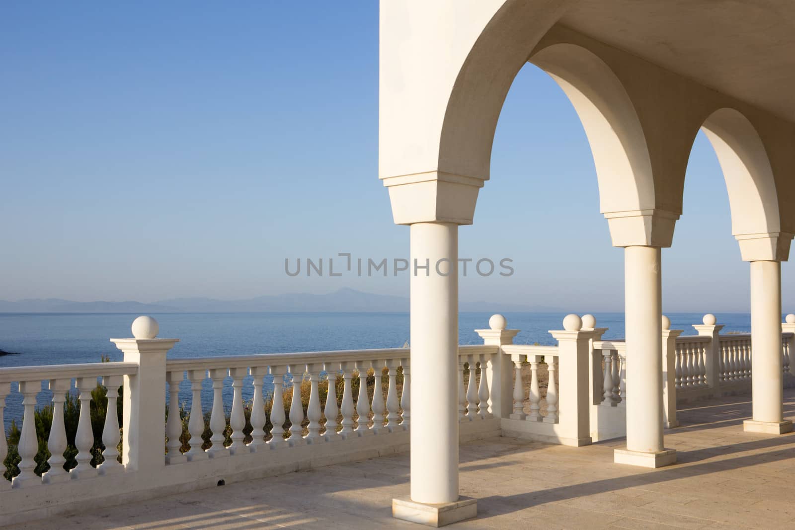 Porch with arches and columns of orthodox church Profitis Ilias in Keratea, near Lavrio, in East Attika, Greece, overlooking the Aegean Sea.