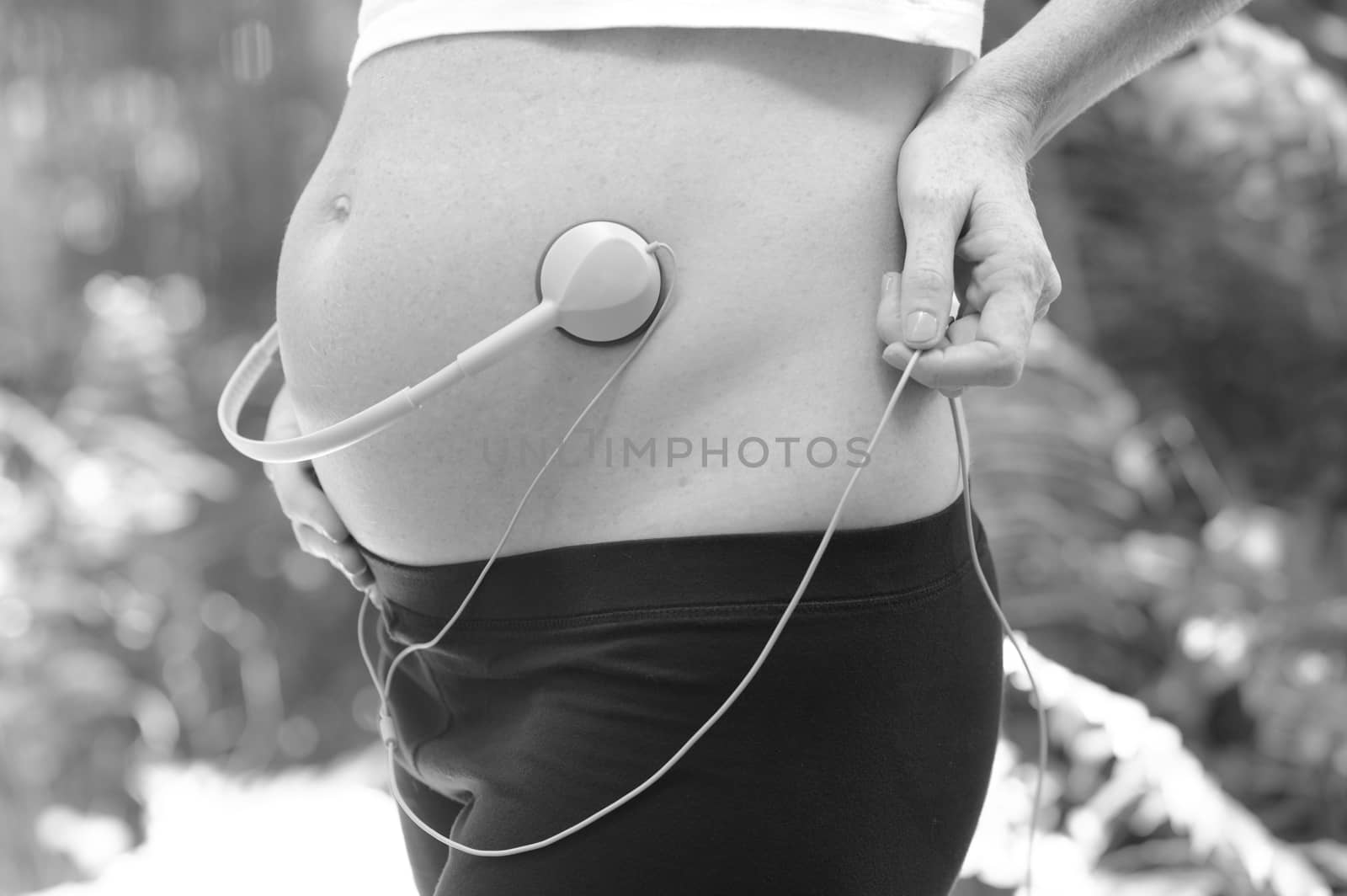 pregnant woman playing music for unborn baby with headphones on stomach