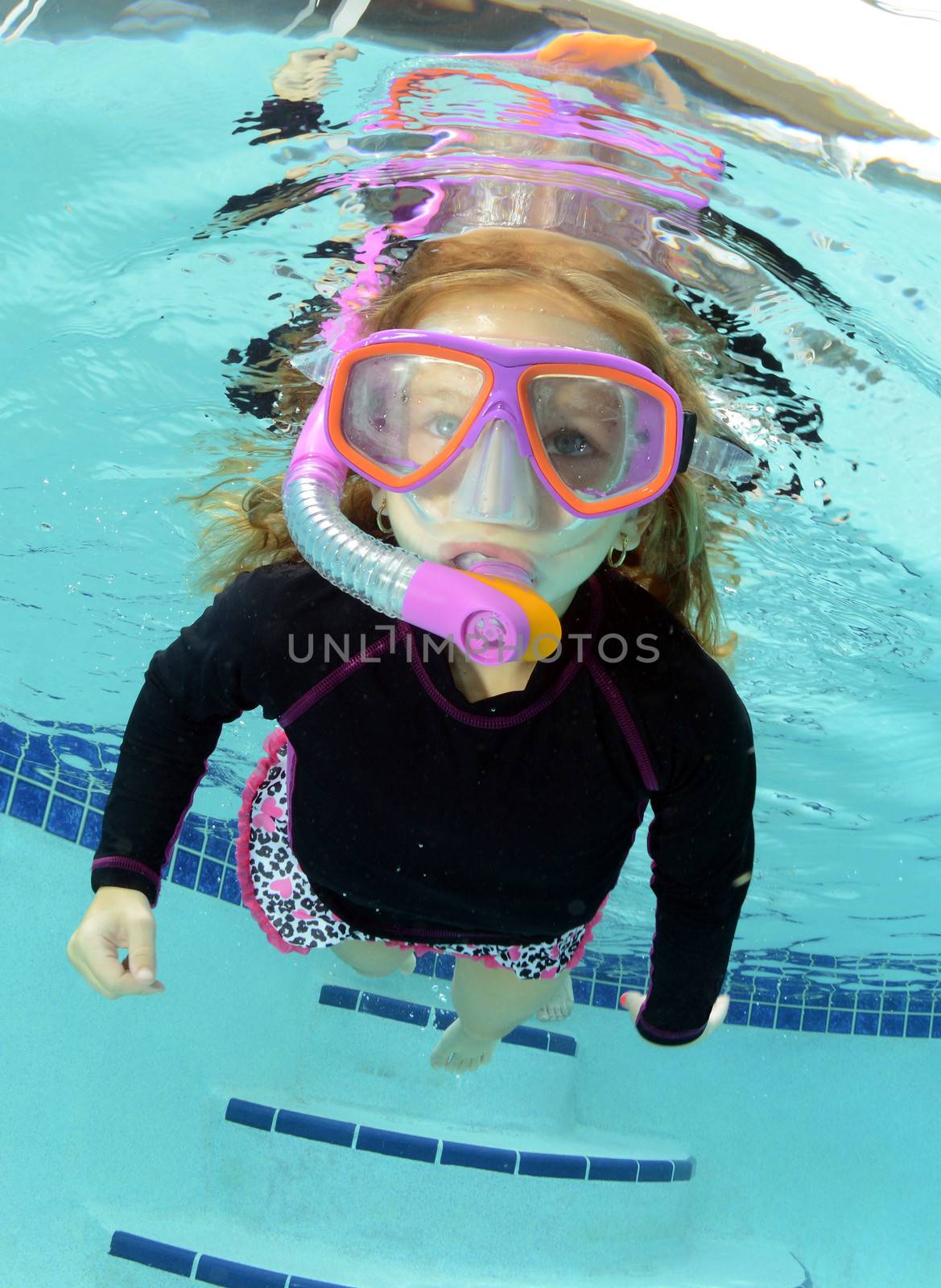 cute child swimming in pool with goggles and snorkel