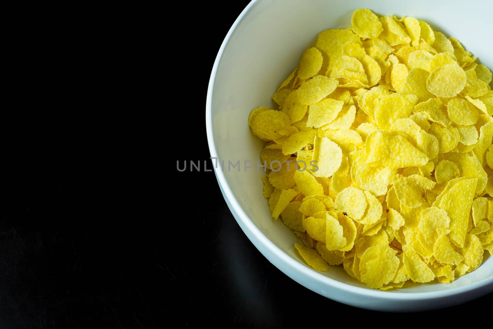 cornflakes in bowl on black table in morning