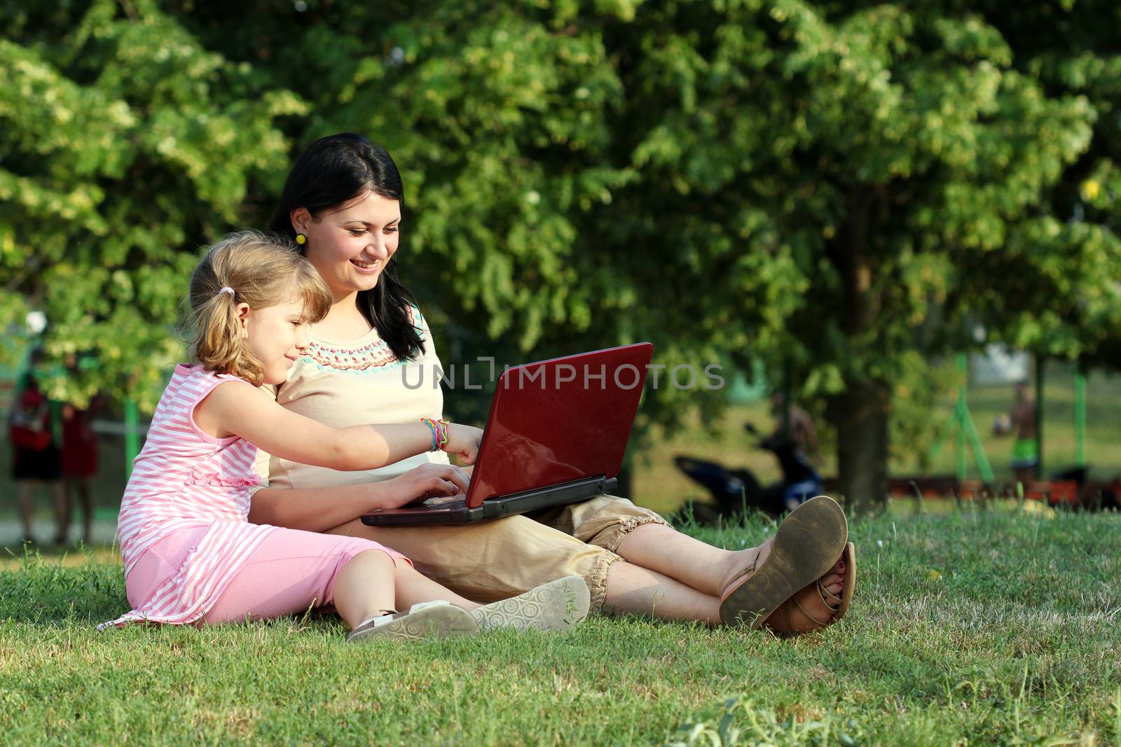 child and girl with laptop in park