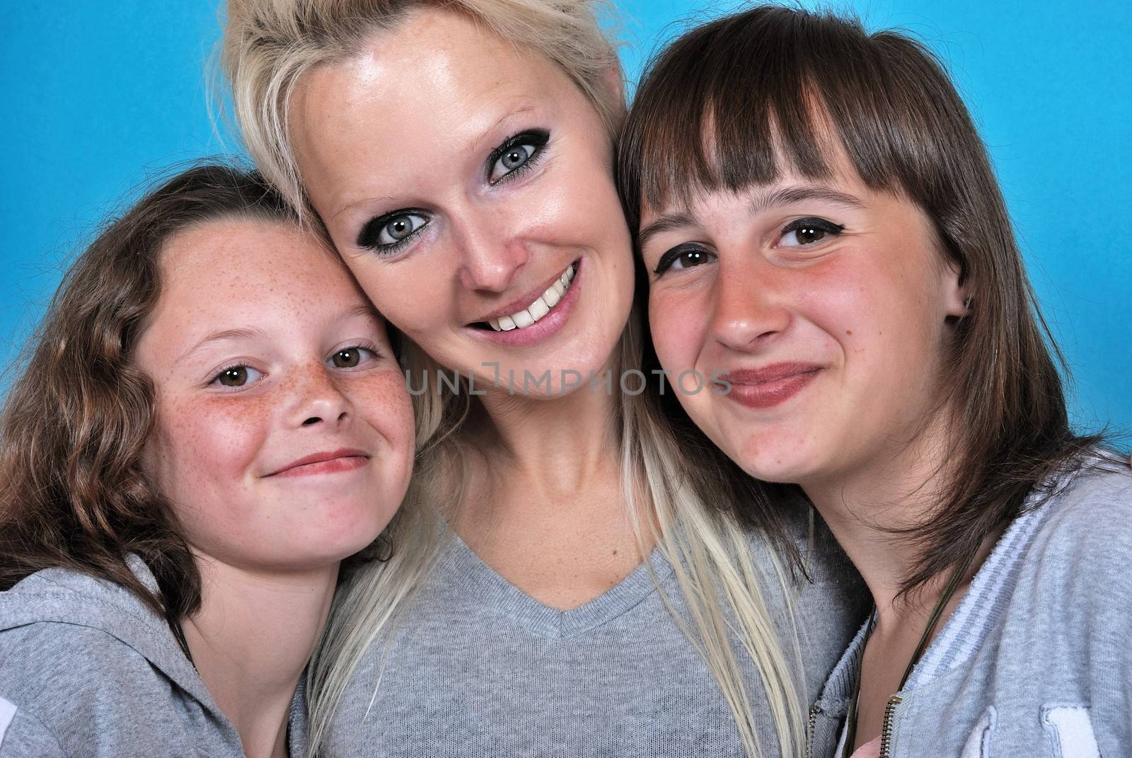 A mother smiles as she receives a kiss on the cheek from her young daughters