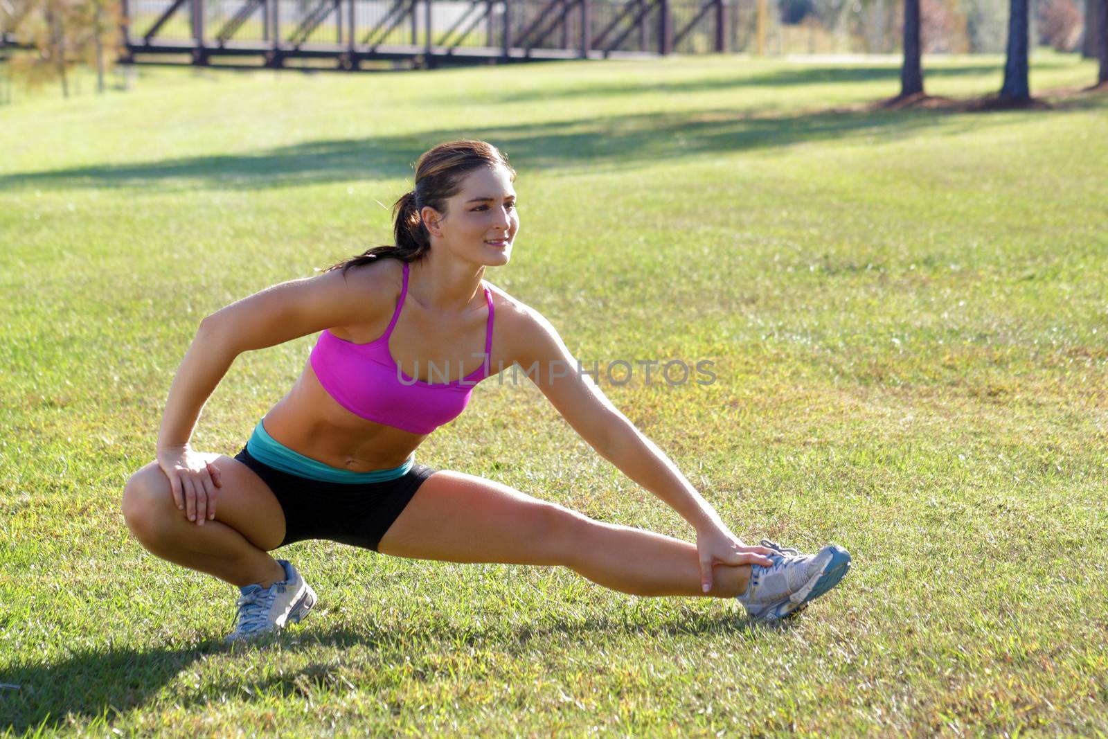 A lovely young brunette with remarkable abdominal musculature does stretching and warm-up outdoors.