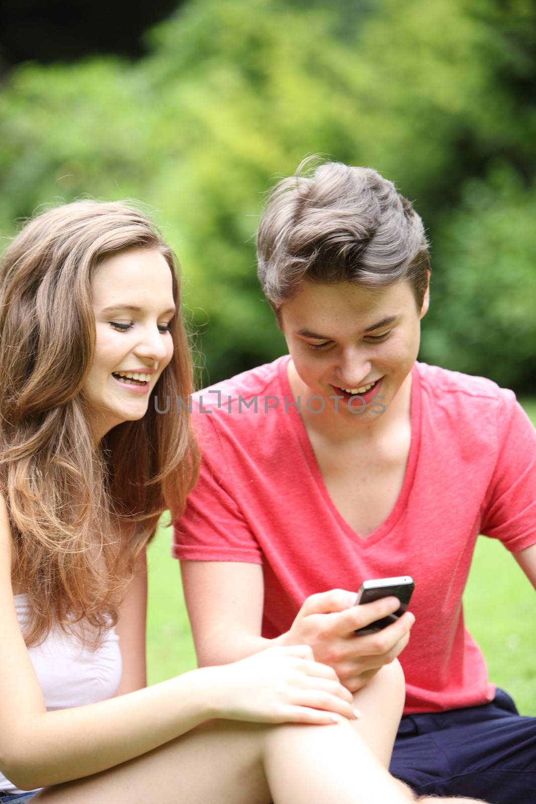 Young teenage couple laughing at an sms by Farina6000