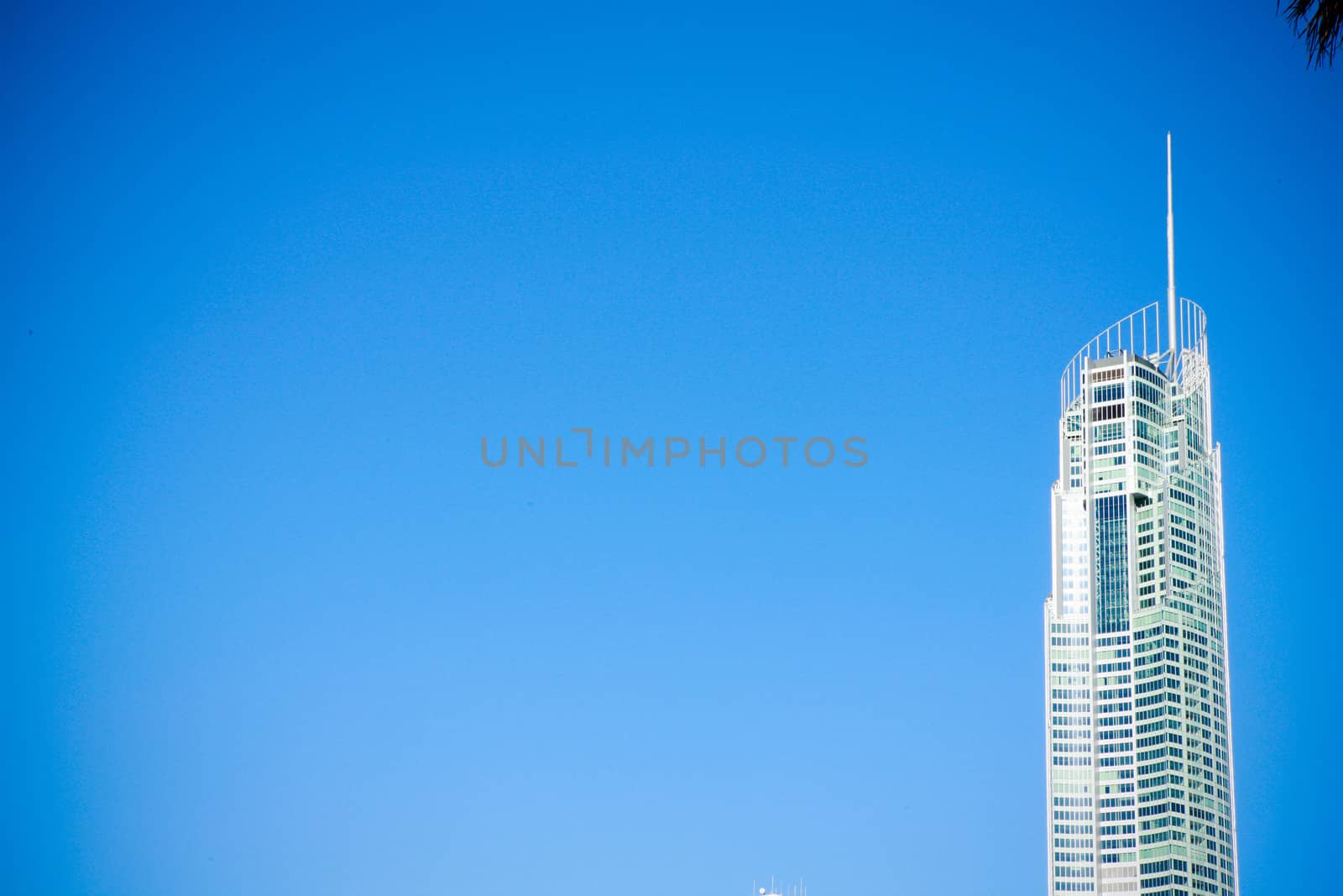 Modern skyscraper housing offices or apartments rising up against a clear blue sunny summer sky with copyspace