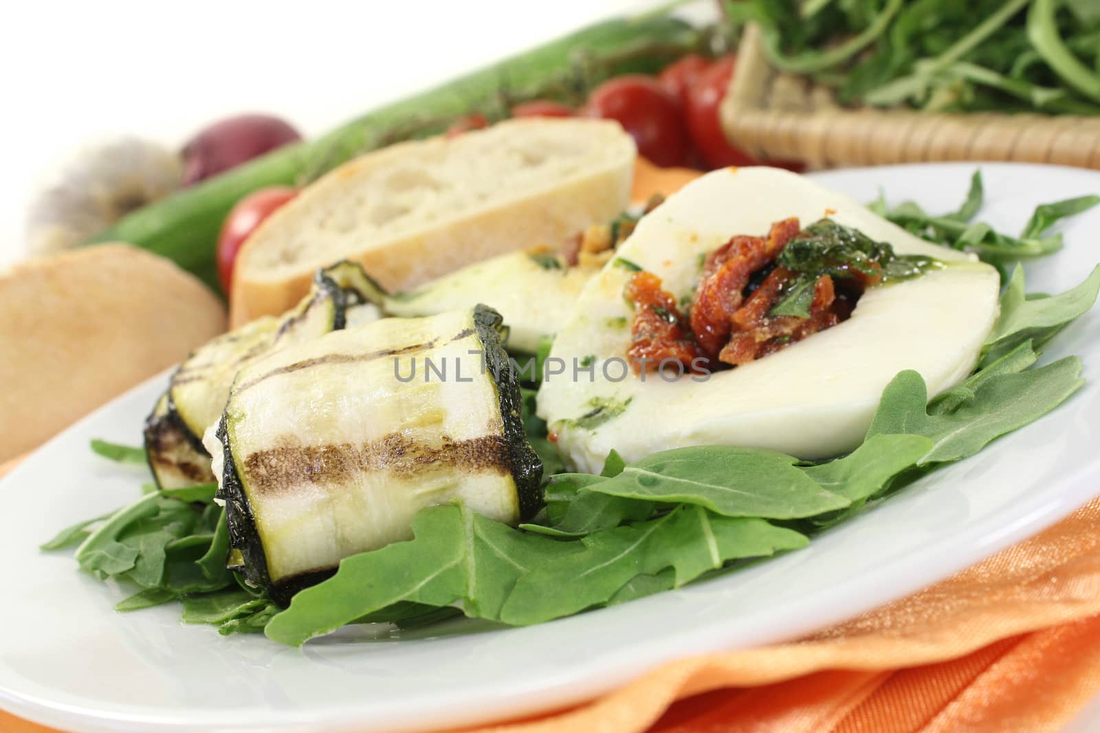 Courgette rolls and filled mozzarella and rocket salad on a bed