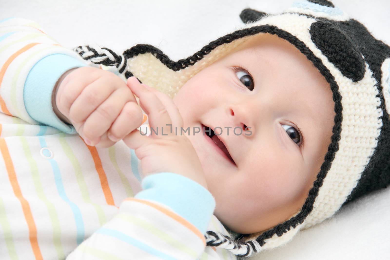 smiling baby lies on back on white bed