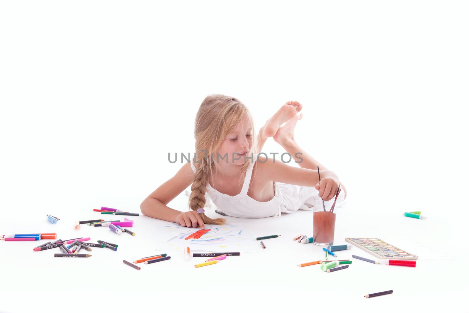 young girl painting with watercolor on floor of studio against white background