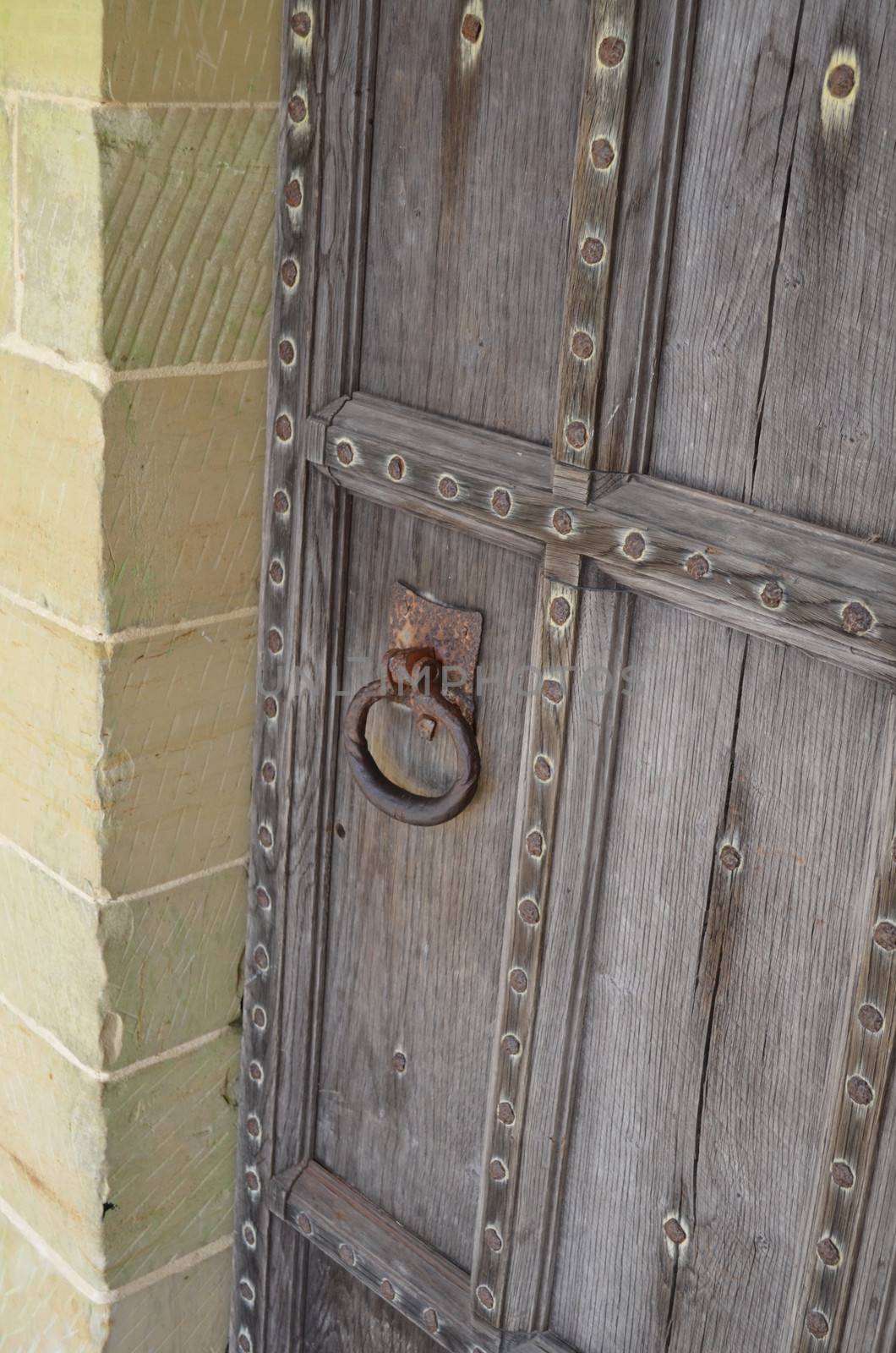 Ancient solid oak door with iron door handle set in a solid stone surround.