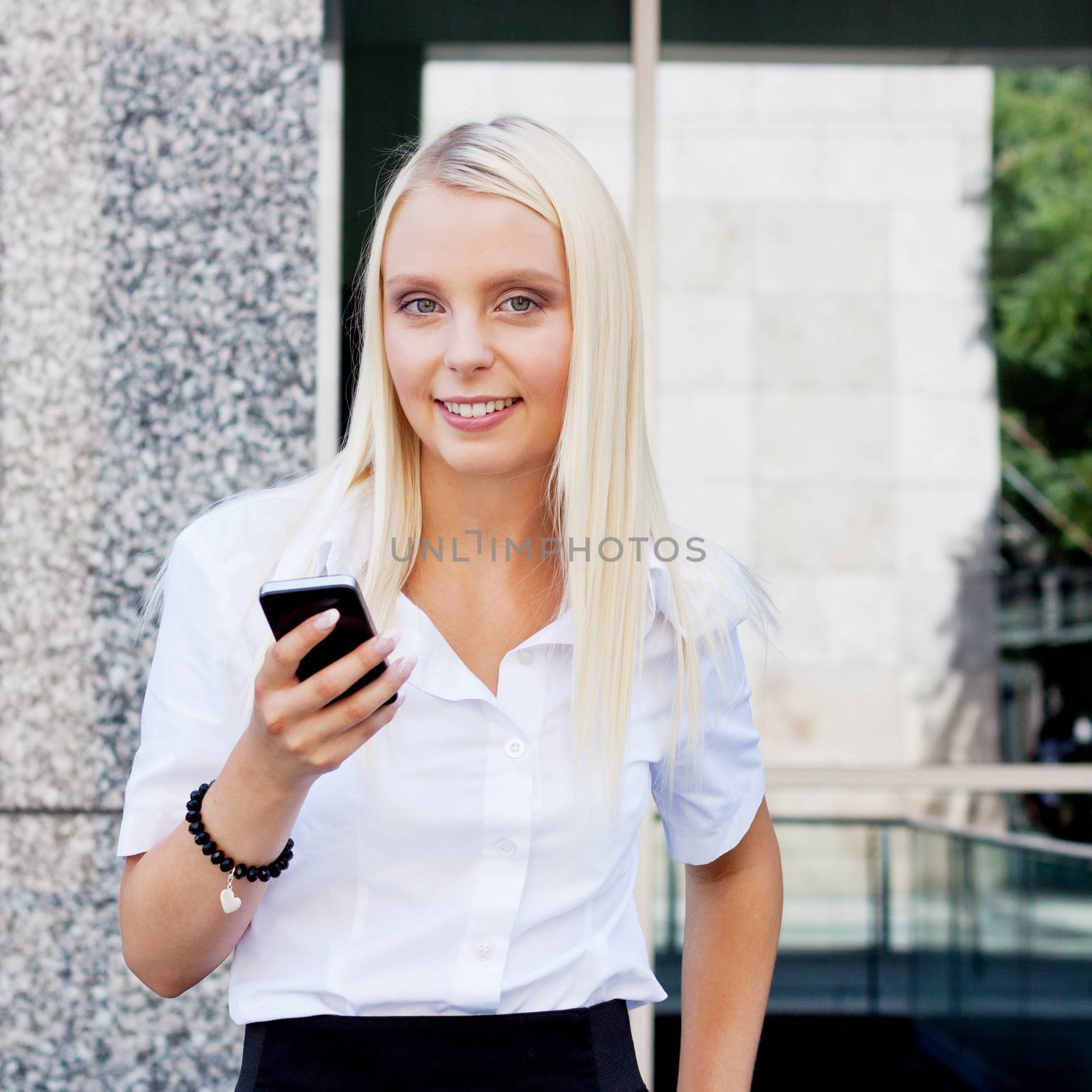 smiling attractive blonde businesswoman with smartphone mobilephone