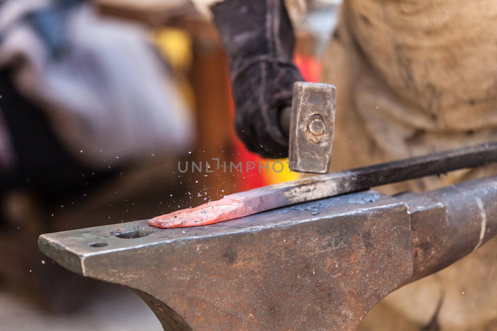 Blacksmith working on metal on anvil at forge detail shot