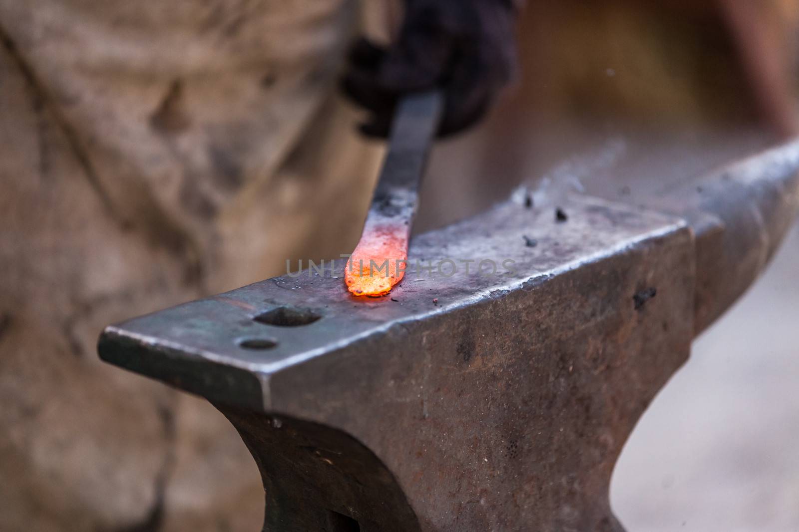 Blacksmith working on metal on anvil at forge detail shot