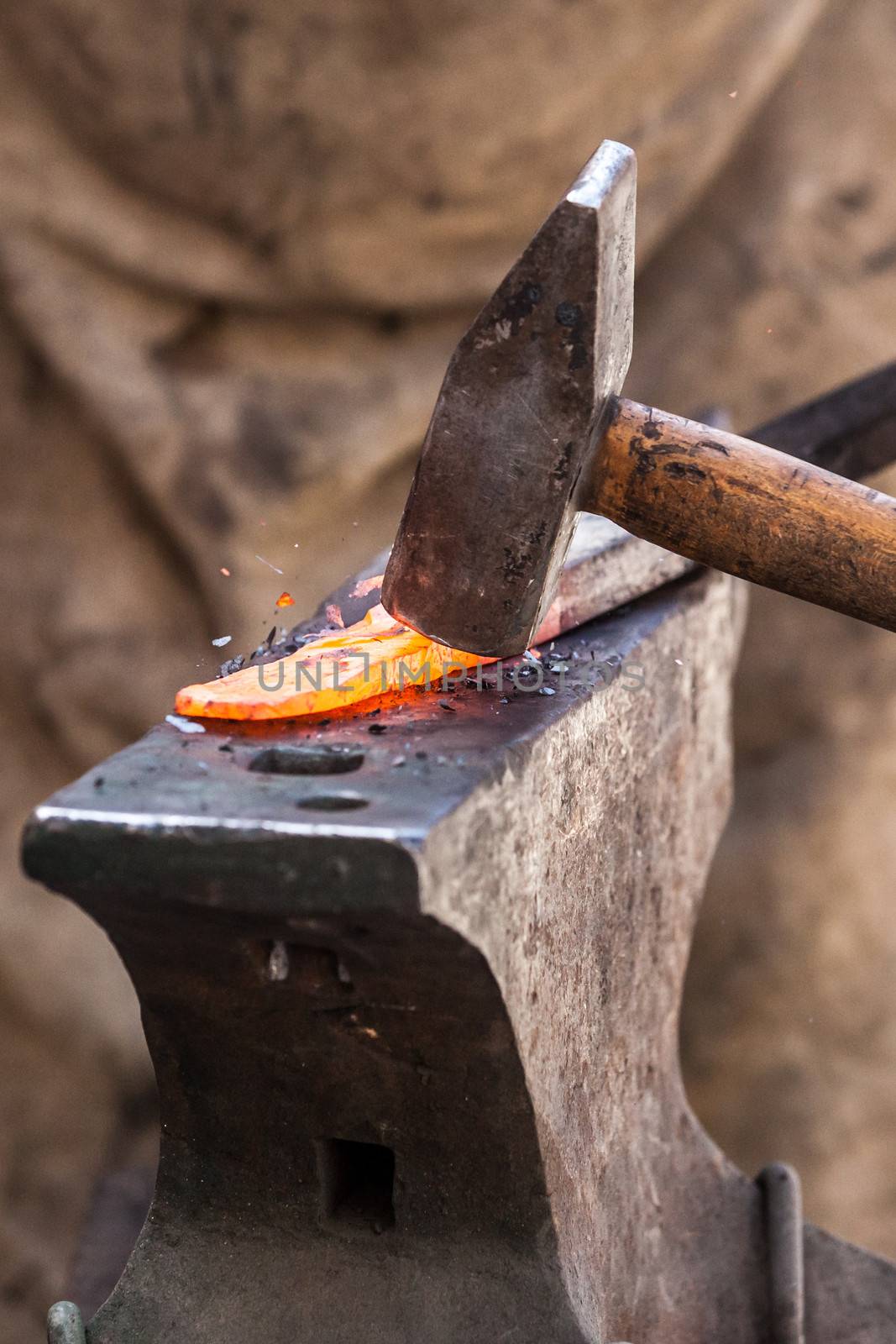 Blacksmith working on metal on anvil at forge detail shot