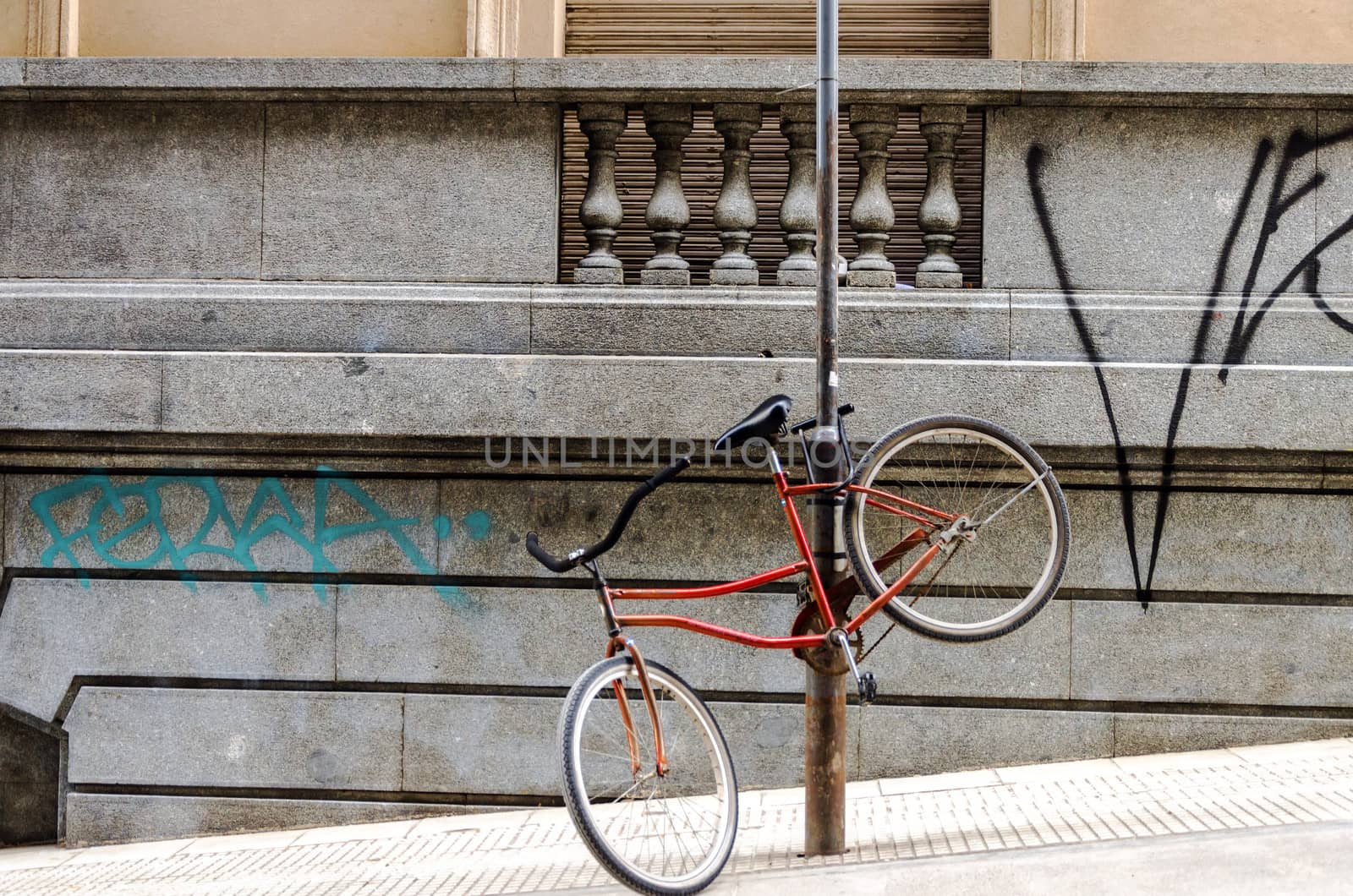 Red bicycle chained to a post in an urban setting