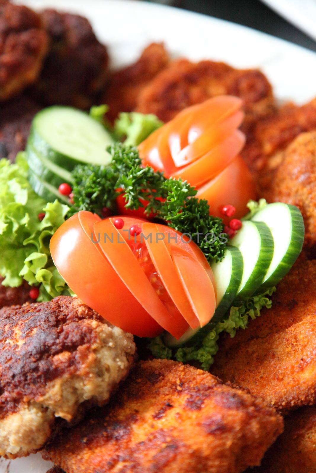 Crumbed fried meat and fish on a buffet table at a catered event with fresh salad ingredients as a garnish