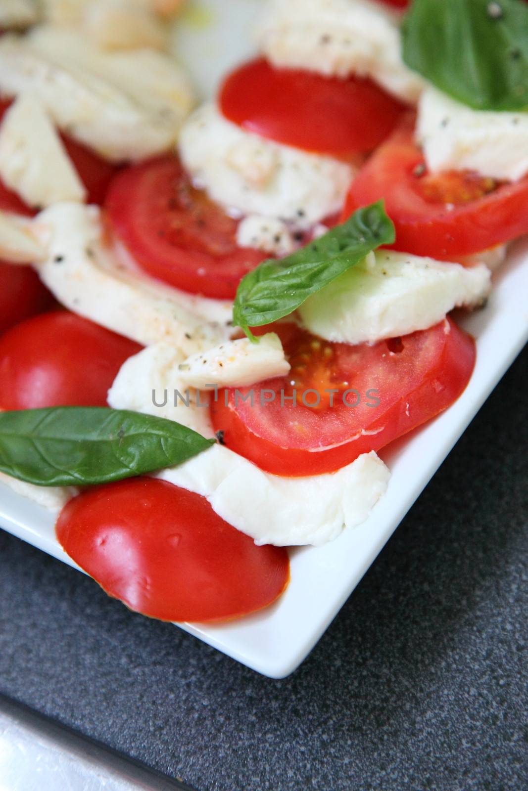 Tomatoes and mozzarella cheese arranged in an alternating pattern on a plate on a buffet table