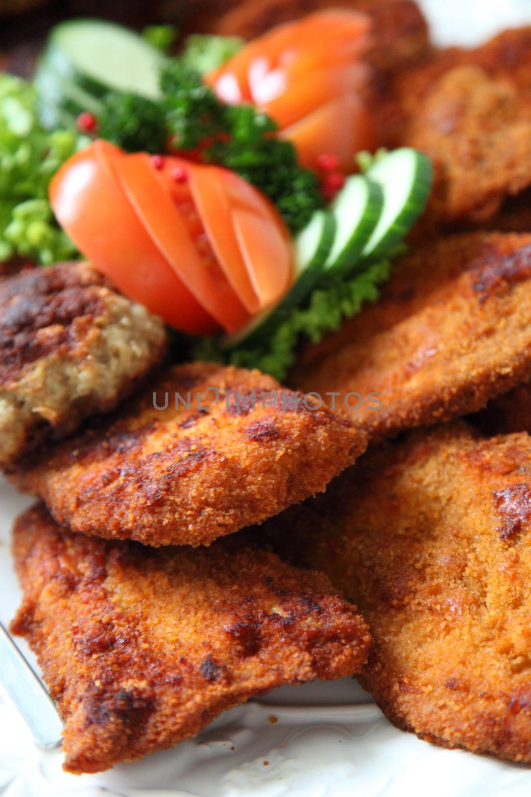 Crumbed fried meat on a buffet table with fresh salads, closeup view with shallow dof