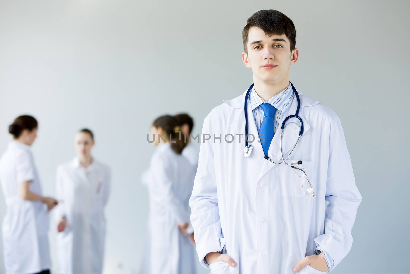 Young doctor in uniform and colleagues at background