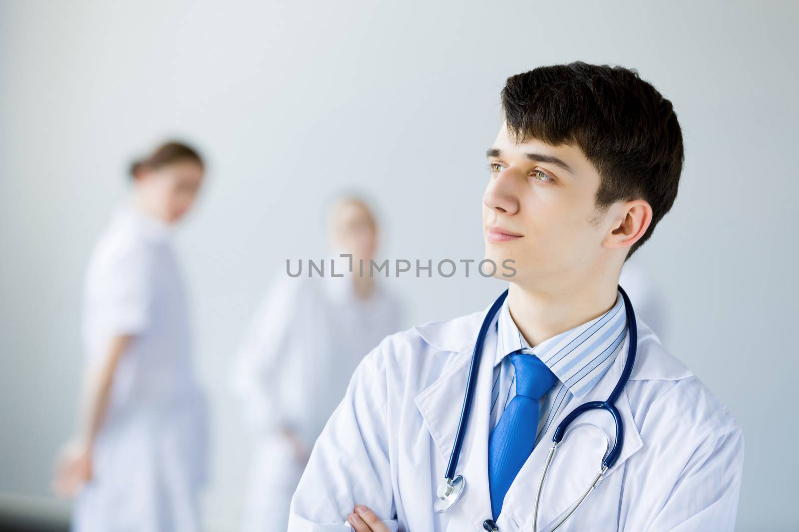 Young doctor in uniform and colleagues at background