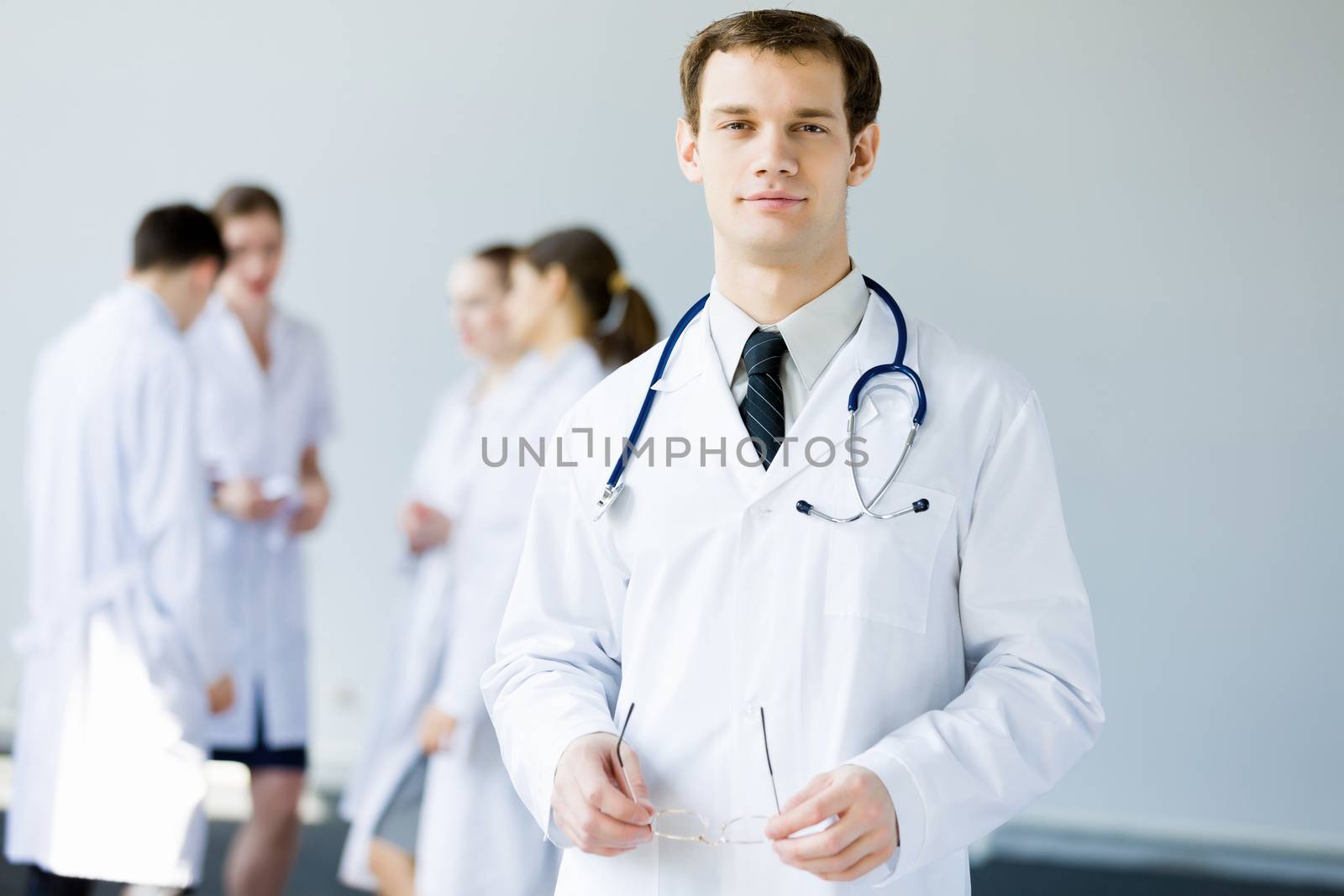 Young doctor in uniform and colleagues at background