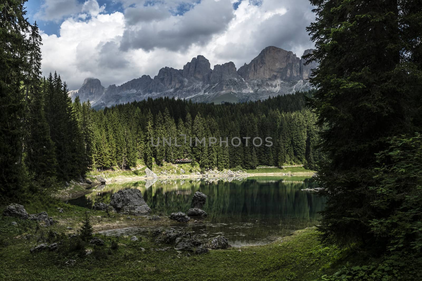 Carezza lake and Catinaccio in summer season with clouds, Dolomites - Italy