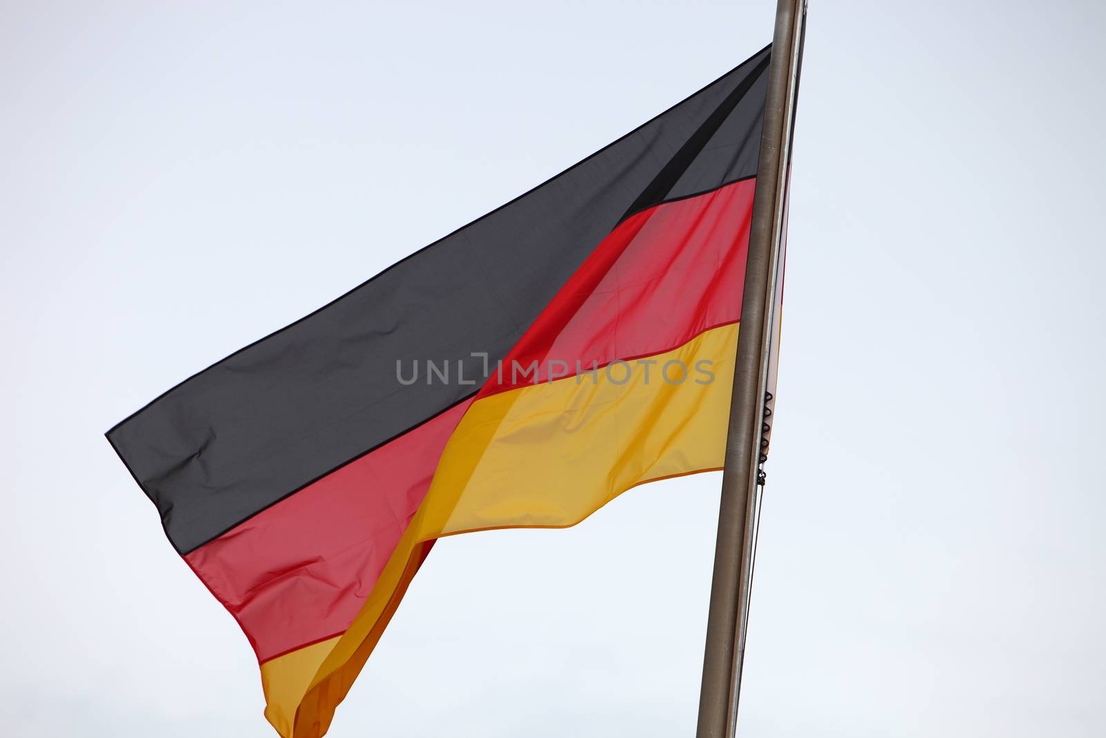 German national flag flying on a flagpole isolated against a light sky