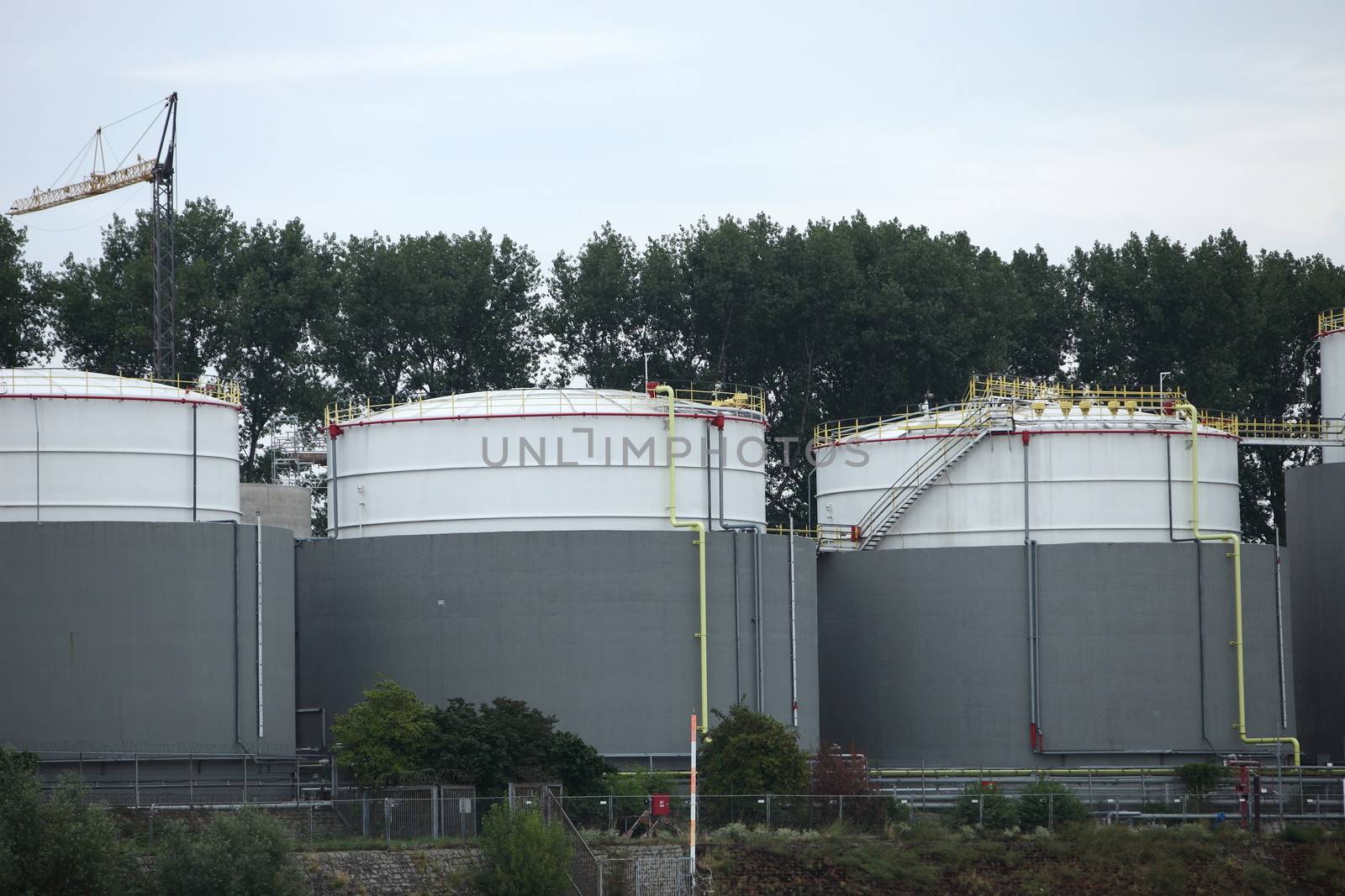 Three metal industrial storage tanks at an industrial site or processing plant