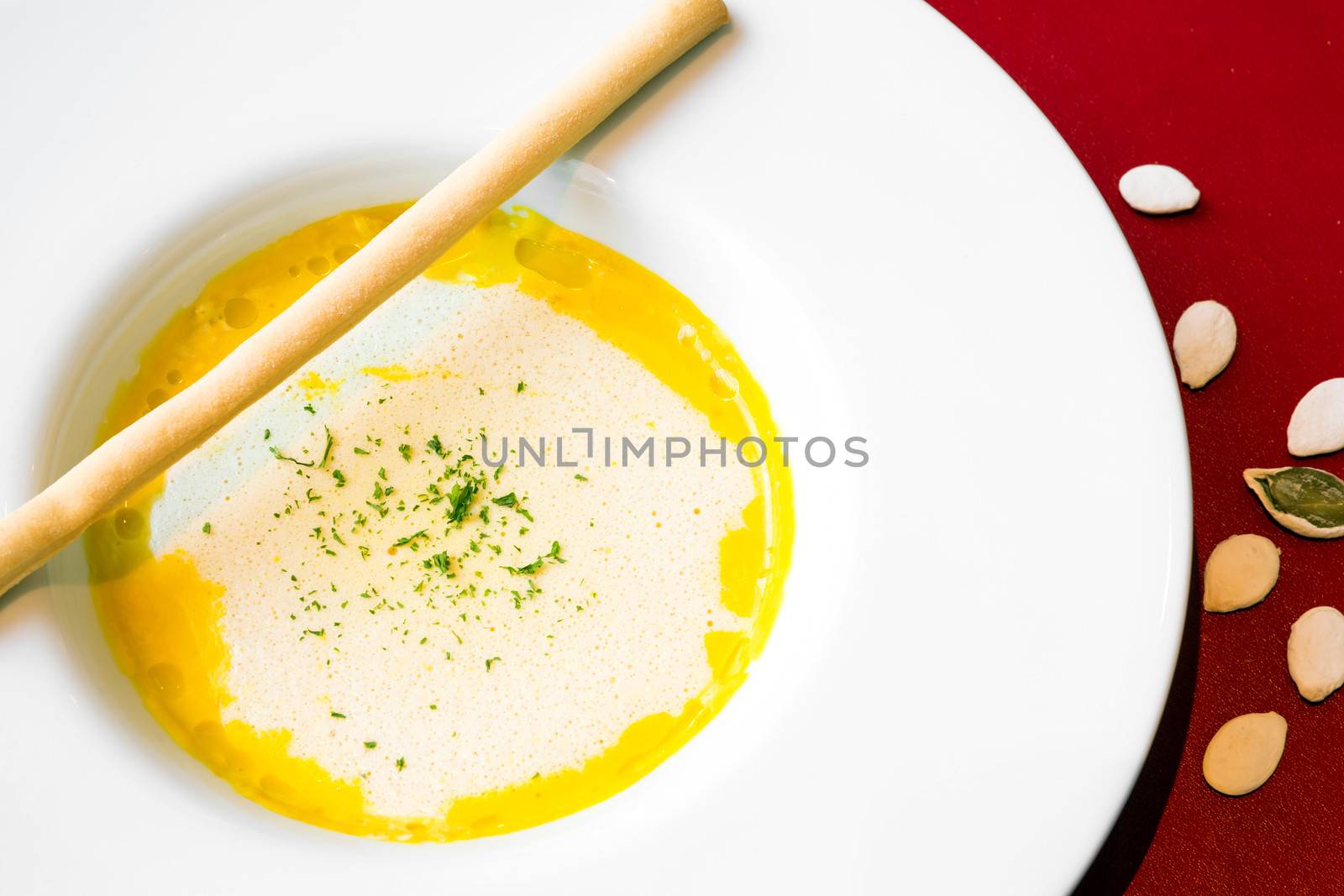 A bowl of pumpkin soup, swirled with coconut cream and bread stick