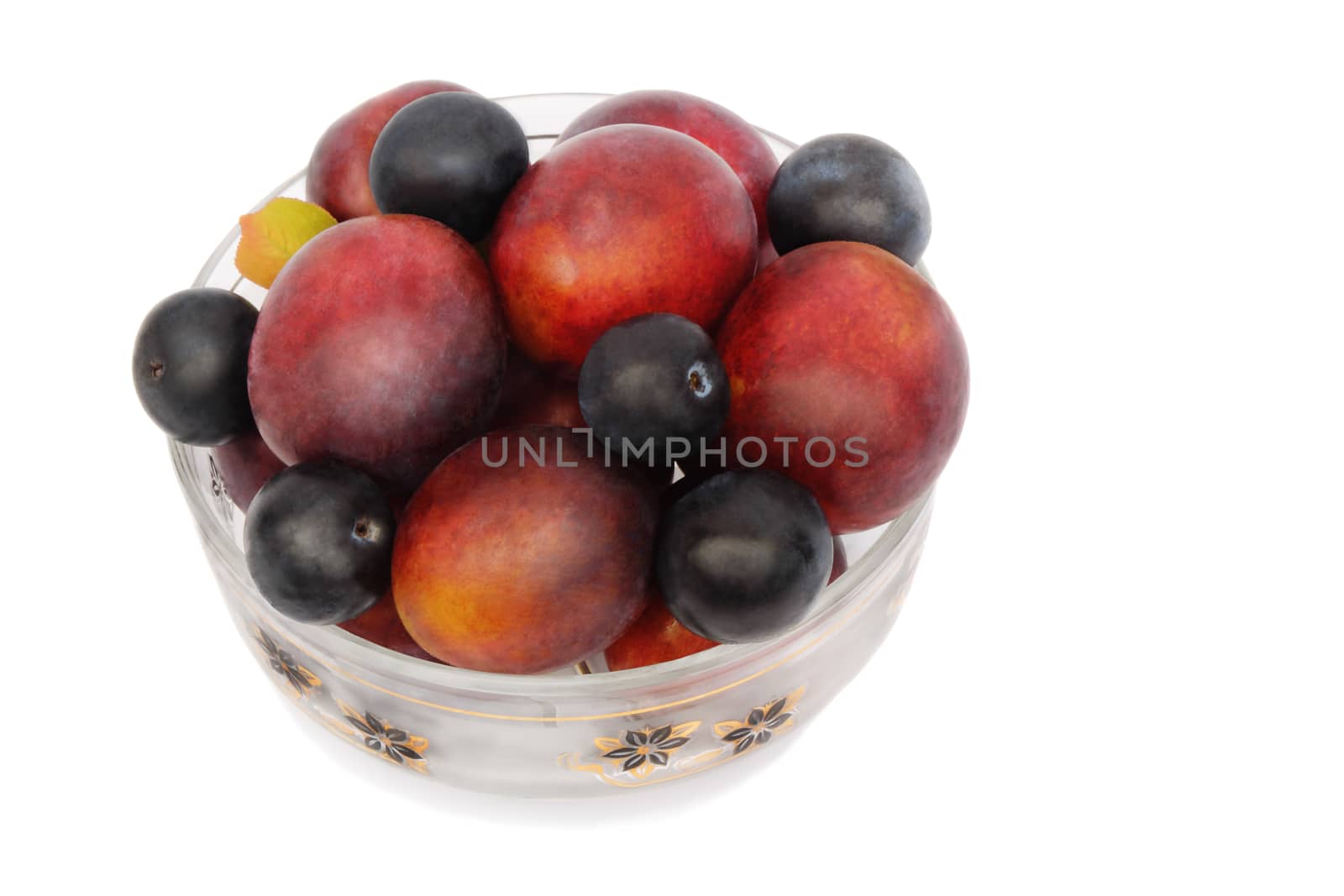 Large ripe plums and prunes in a vase for fruit. Presented on a white background.