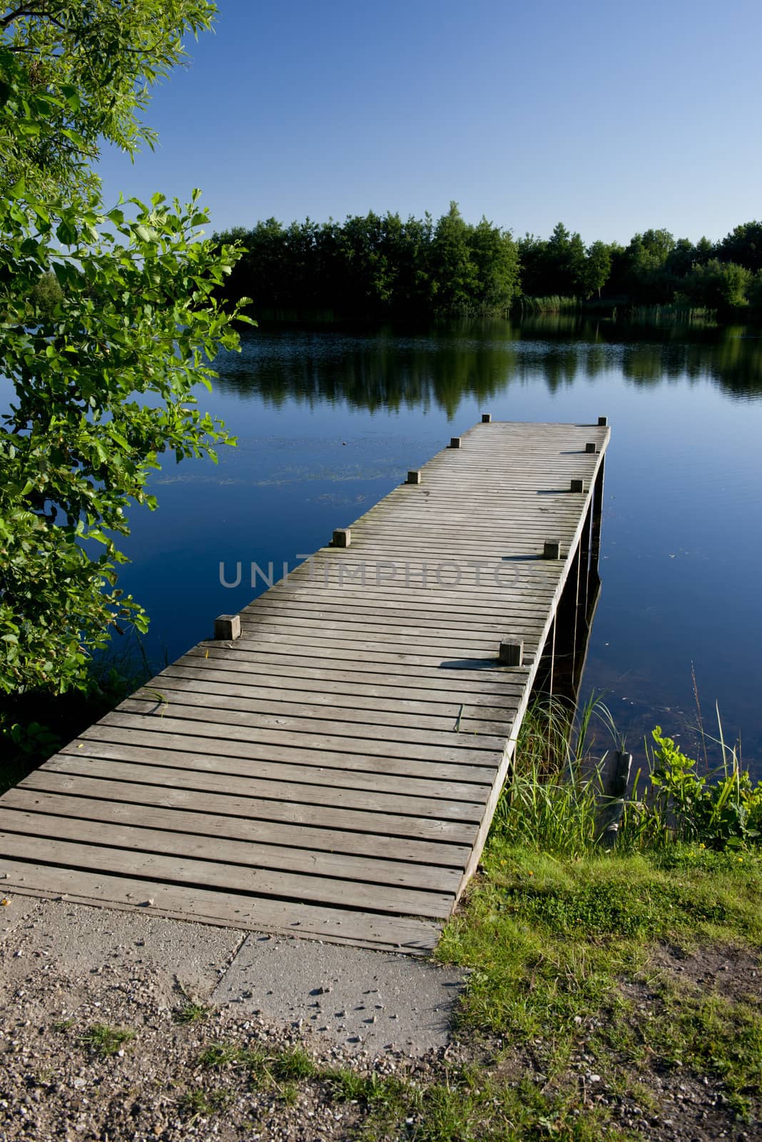  wooden pier on a quiet blue pond in Denmark