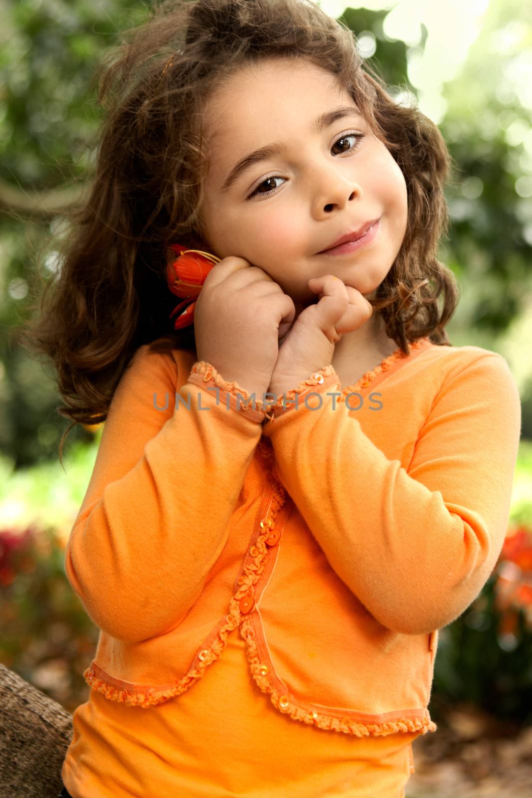 Adorable little girl holding a flower picked from the garden and smiling.