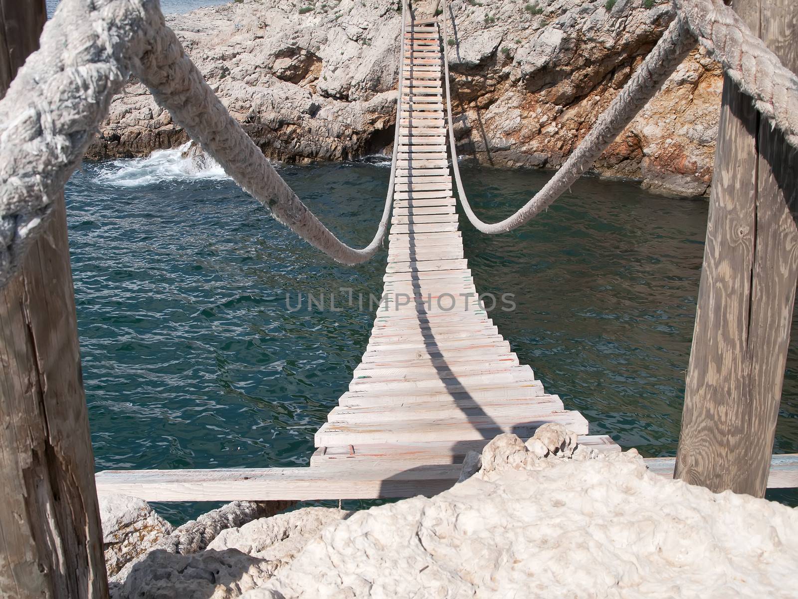 hanging wooden bridge connect rocky seacost