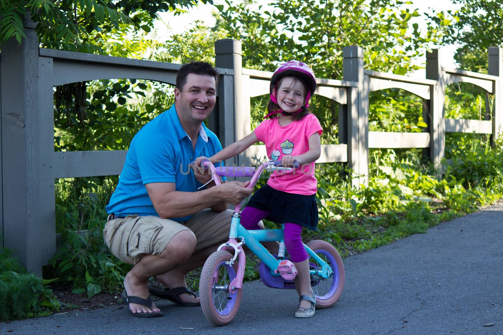 Child learning to ride a bicycle with father