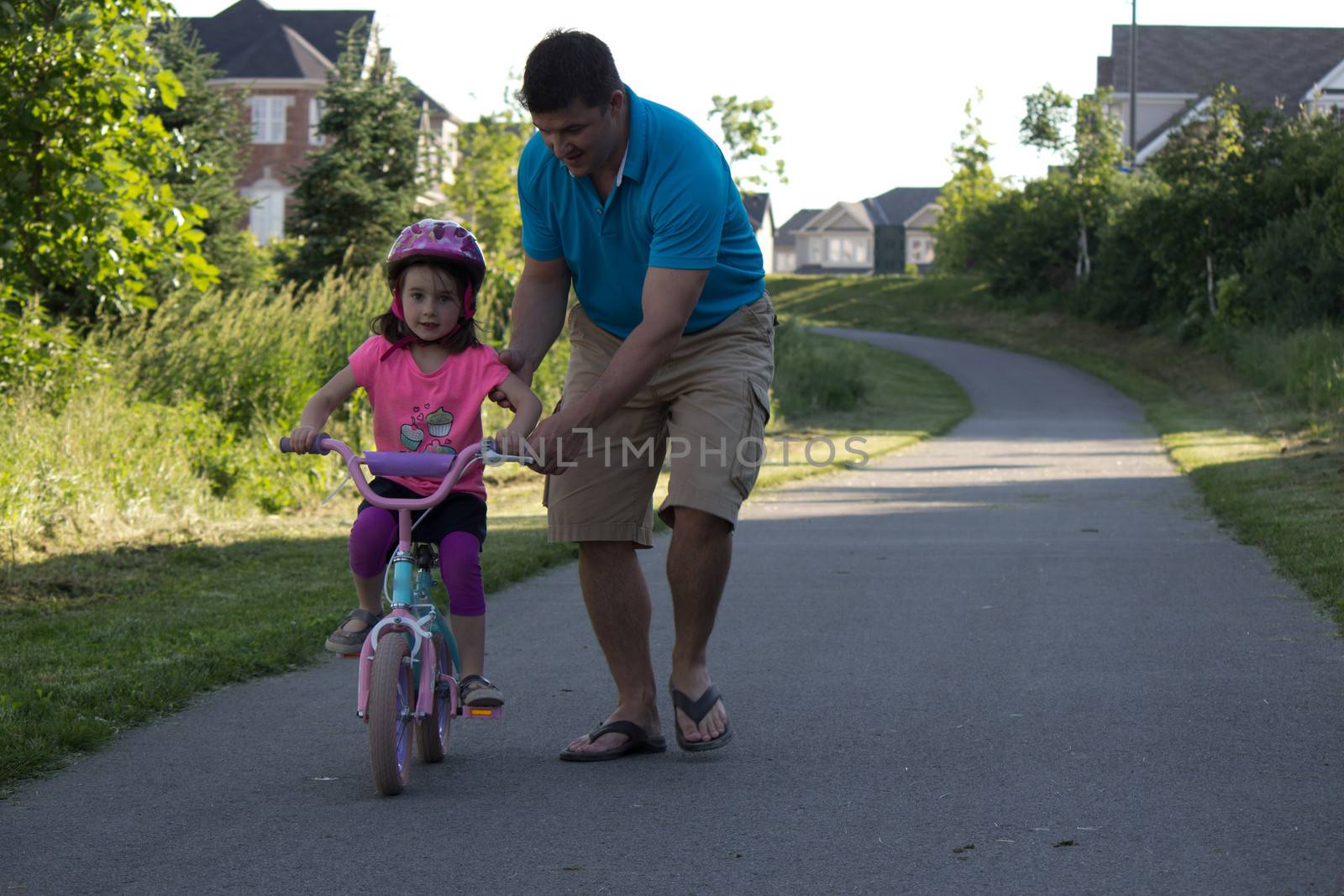 Child learning to ride a bicycle with father