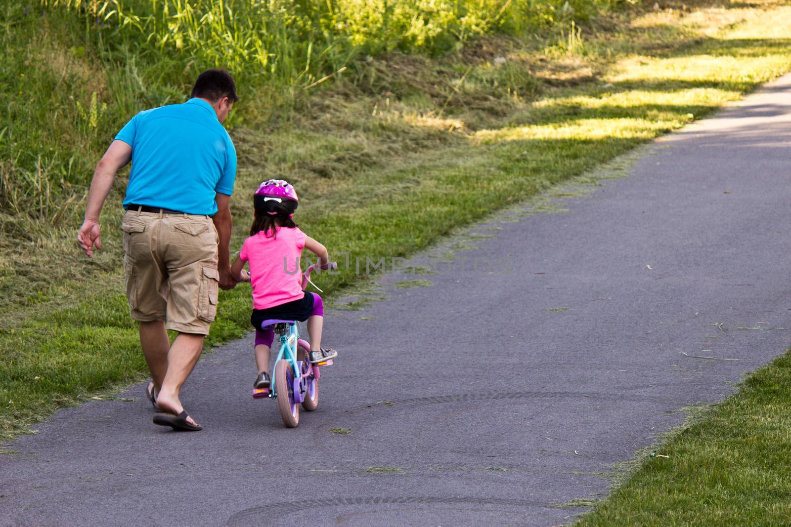 Child learning to ride a bicycle with father by bigjohn36