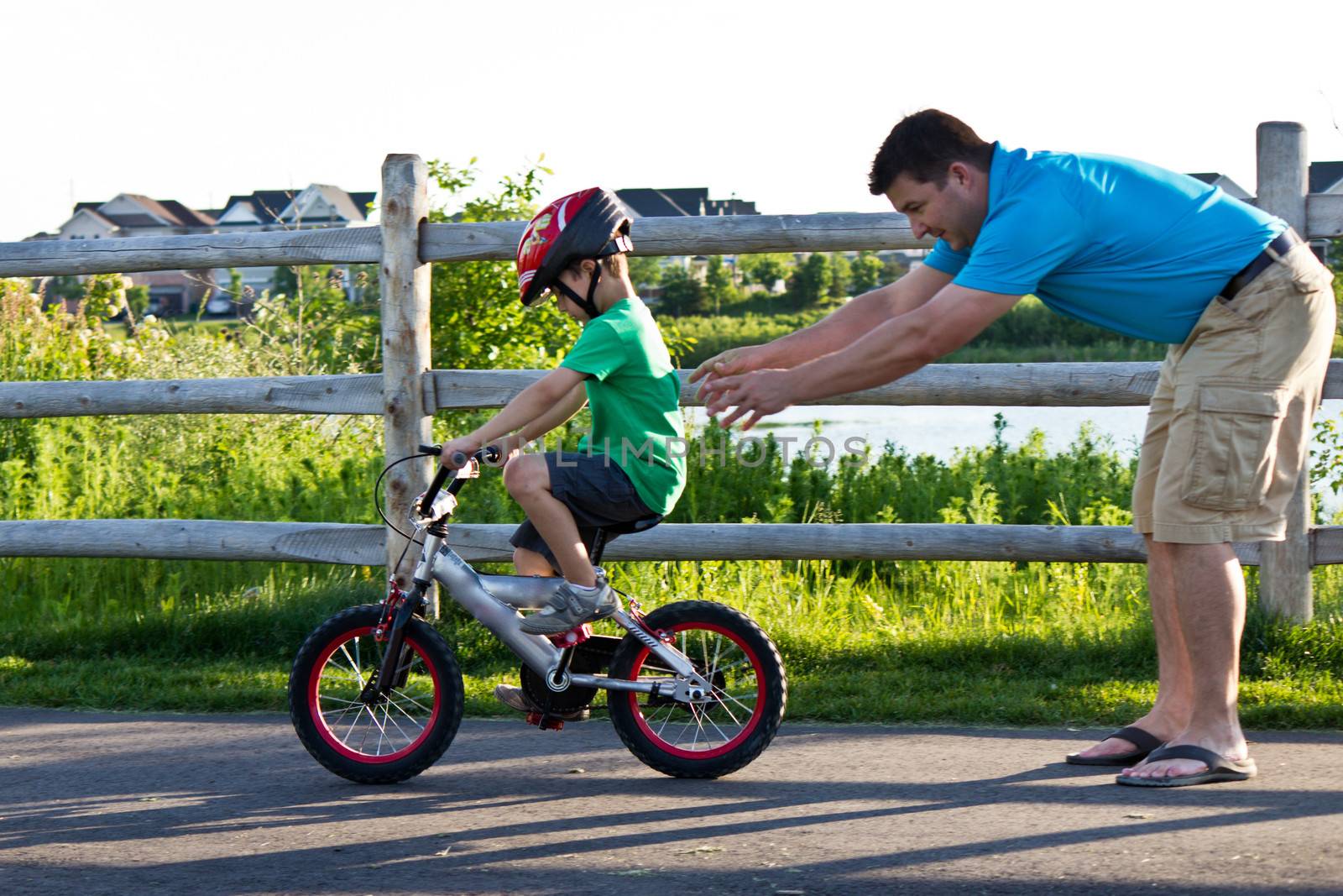 Child learning to ride a bicycle with father by bigjohn36