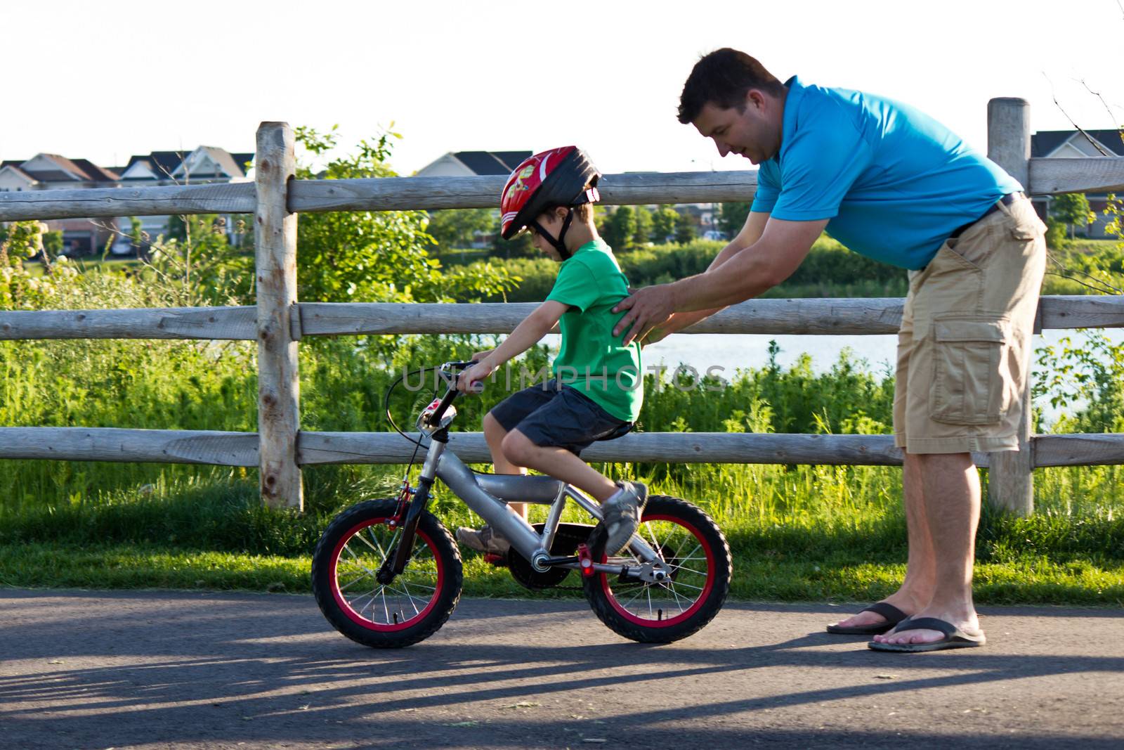 Child learning to ride a bicycle with father by bigjohn36