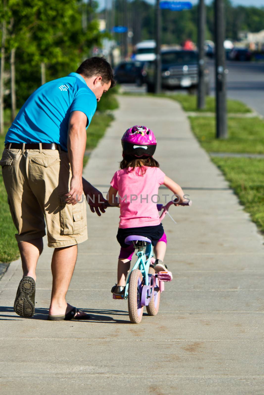 Child learning to ride a bicycle with father by bigjohn36