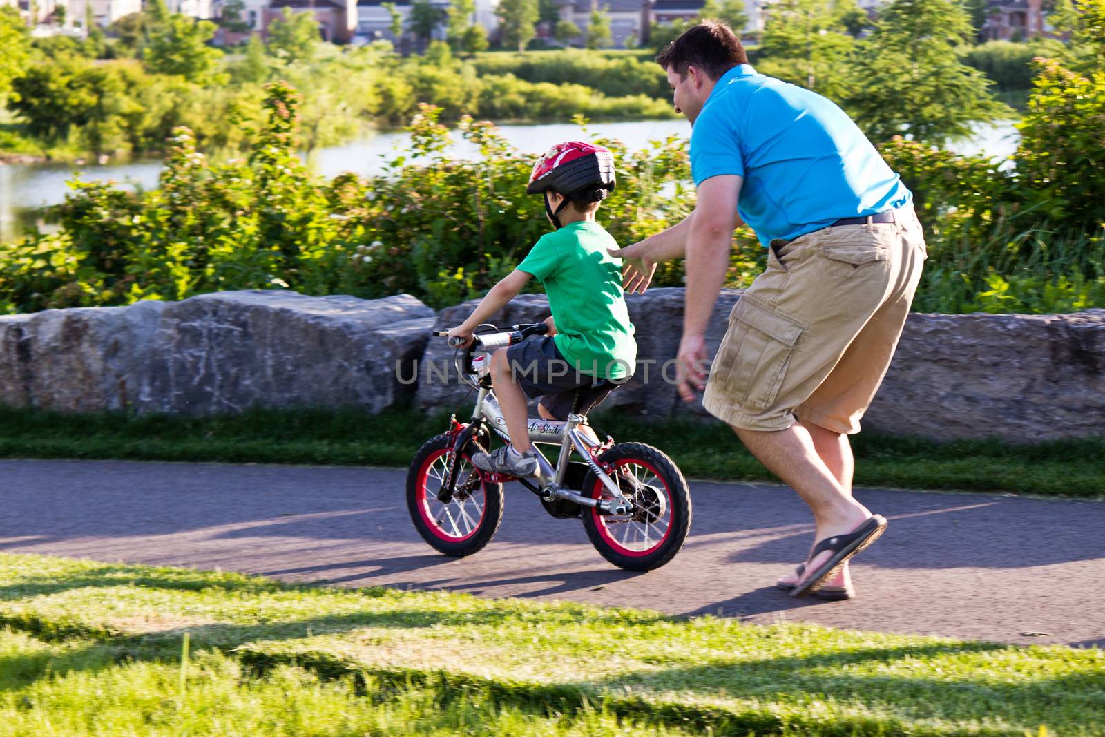 Child learning to ride a bicycle with father by bigjohn36