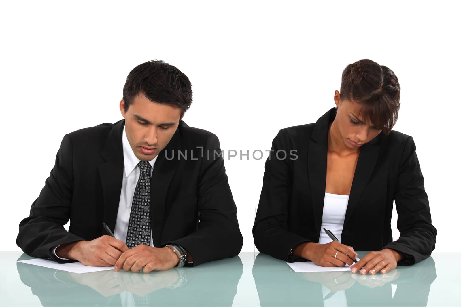 Two business people writing at a desk