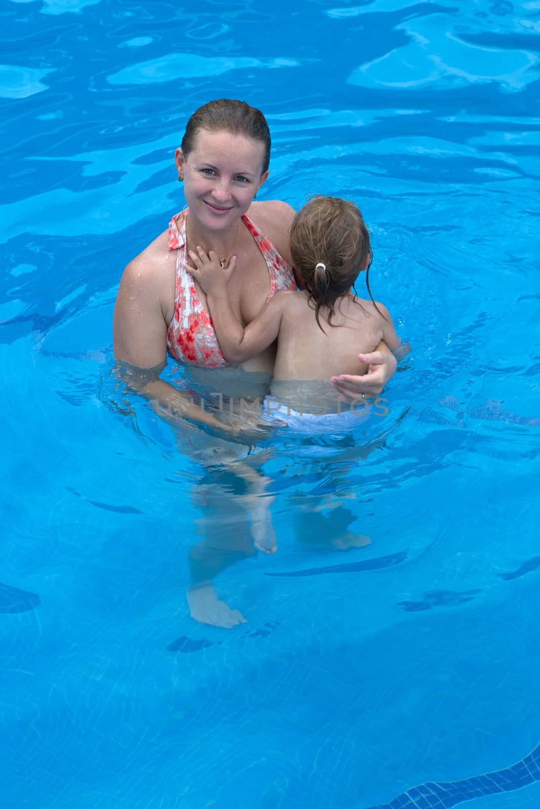 Mother holding her daughter in the swimming pool perhaps teaching her swimming