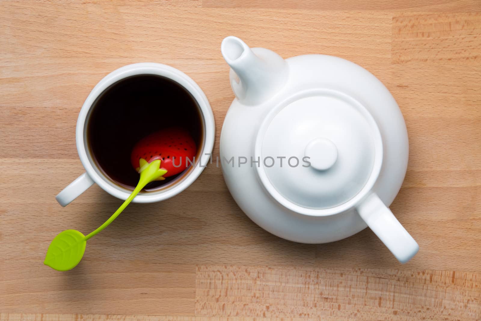Infused tea and teapot  next to each other on beech wood, shot from top