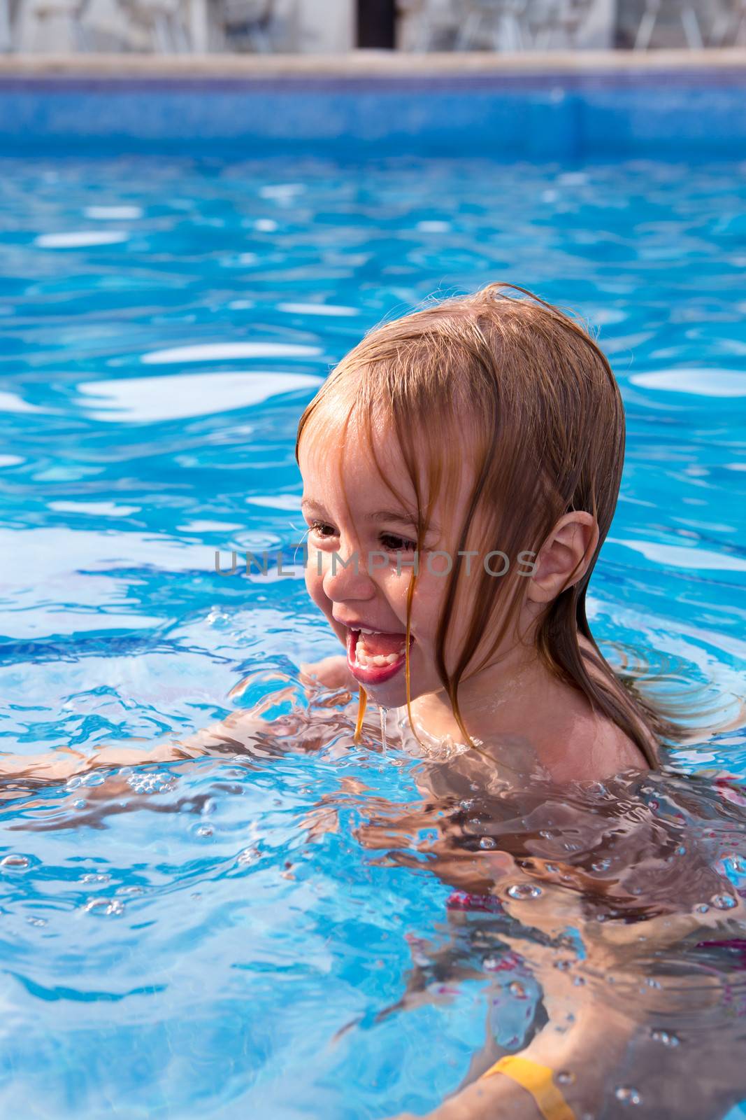 Cute toddler learning how to swim while having fun in the swimming pool